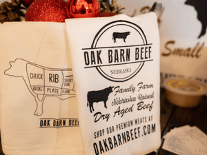 Tea towels with black designs that say Oak Barn Beef and represent the company.