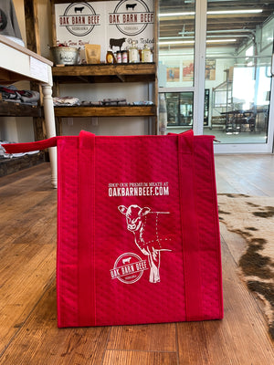 Red insulated grocery tote with design of cow and Oak Barn Beef logo and text that says 'Shop our premium meats at oakbarnbeef.com'