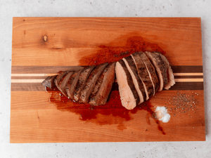 Tri Tip beef Roast cooked and on a cutting board with a white background.